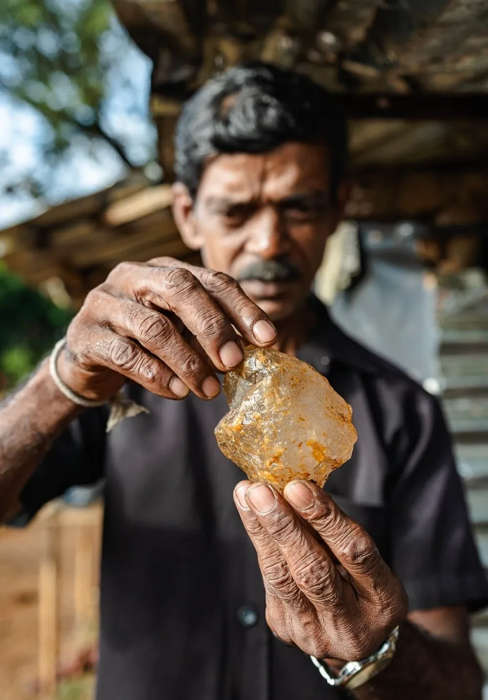 A gem miner examining a rough Ceylon stone